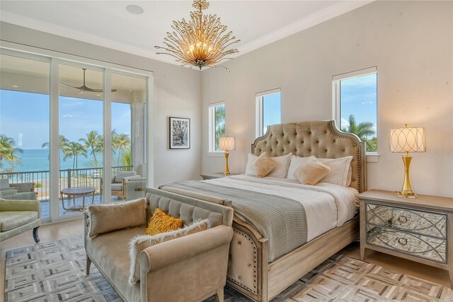 bedroom with access to exterior, a water view, light hardwood / wood-style floors, and a notable chandelier