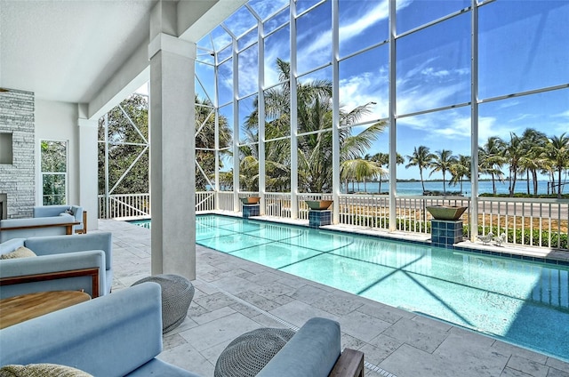 view of pool featuring glass enclosure, a water view, and a patio