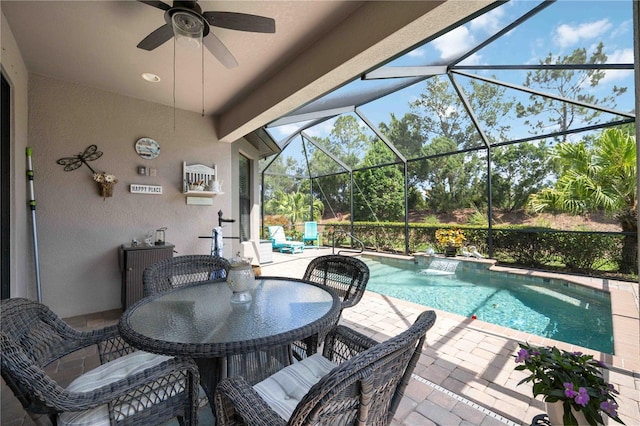 view of pool with pool water feature, glass enclosure, ceiling fan, and a patio area