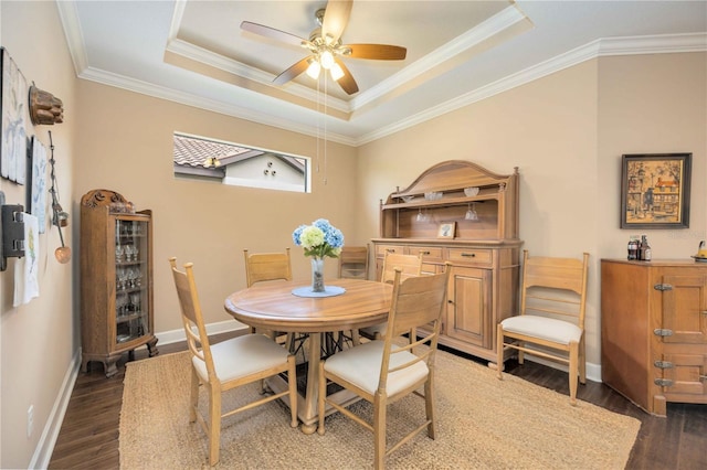 dining room with a raised ceiling, dark hardwood / wood-style flooring, and crown molding