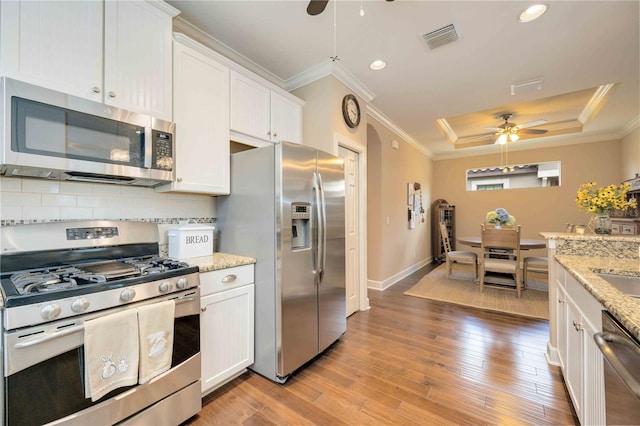 kitchen featuring white cabinets, light hardwood / wood-style flooring, decorative backsplash, light stone countertops, and appliances with stainless steel finishes