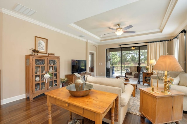 living room with dark hardwood / wood-style floors, ceiling fan, crown molding, and a tray ceiling