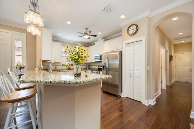 kitchen with hanging light fixtures, stainless steel appliances, white cabinetry, and dark hardwood / wood-style floors