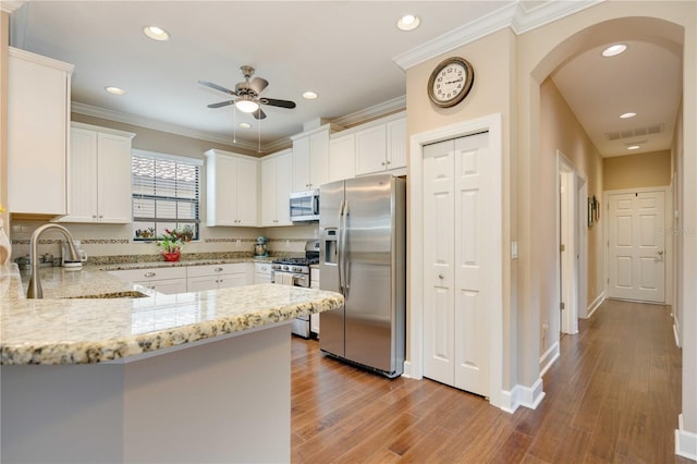 kitchen featuring white cabinetry, sink, stainless steel appliances, light stone counters, and hardwood / wood-style floors