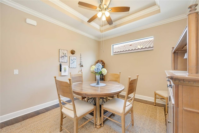 dining area with wood-type flooring, a tray ceiling, ceiling fan, and ornamental molding