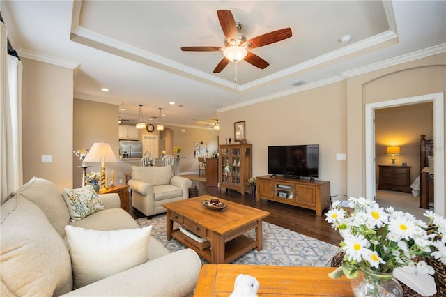 living room featuring ceiling fan, a raised ceiling, crown molding, and light hardwood / wood-style flooring