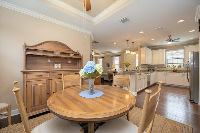 dining area featuring sink, ceiling fan, crown molding, and dark wood-type flooring