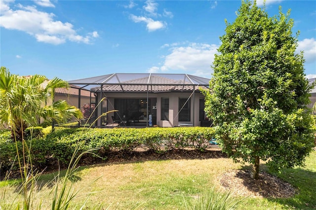 back of house featuring a lawn and glass enclosure