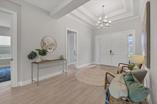 entrance foyer with an inviting chandelier, ornamental molding, and light hardwood / wood-style flooring