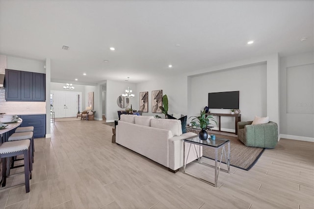 living room with light hardwood / wood-style floors and a notable chandelier