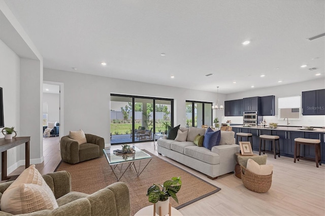 living room featuring light hardwood / wood-style floors, sink, and a chandelier