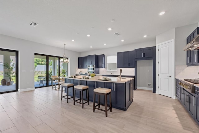 kitchen featuring a center island with sink, decorative light fixtures, and a breakfast bar area