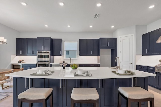 kitchen with sink, a spacious island, a breakfast bar area, and double oven