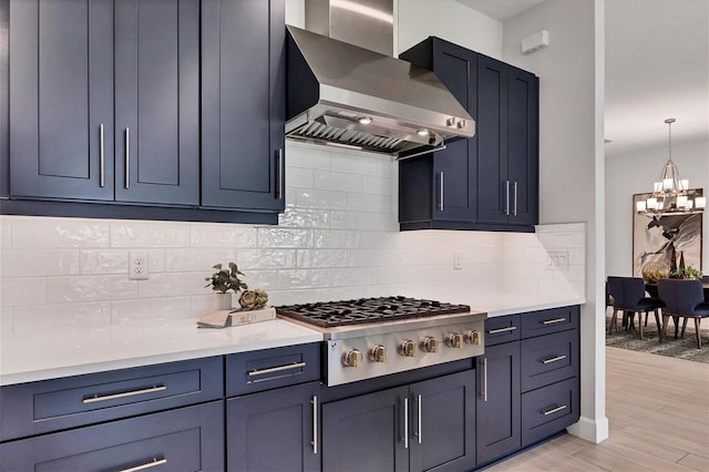 kitchen with wall chimney exhaust hood, hanging light fixtures, stainless steel gas cooktop, decorative backsplash, and light wood-type flooring