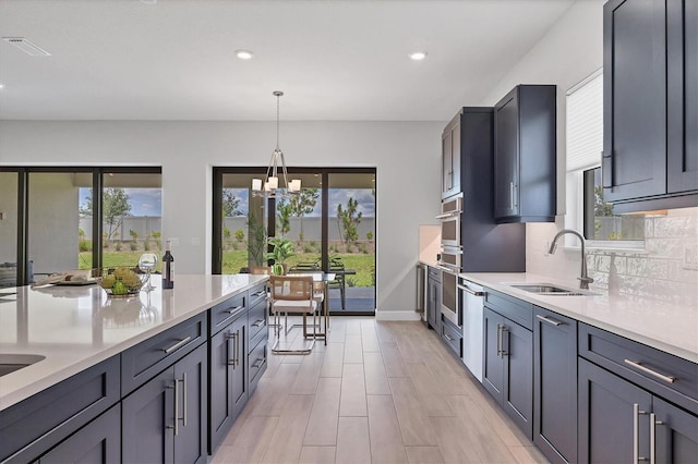 kitchen with light wood-type flooring, backsplash, sink, decorative light fixtures, and an inviting chandelier