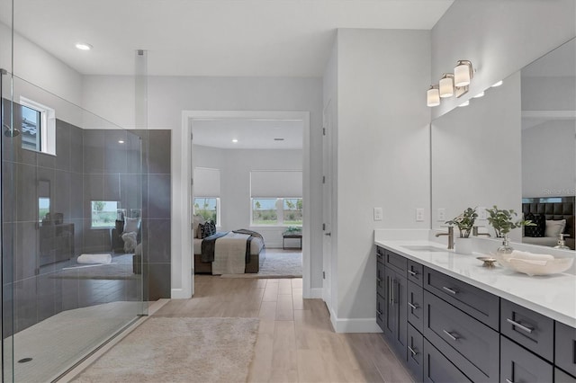 bathroom with tiled shower, vanity, and hardwood / wood-style flooring