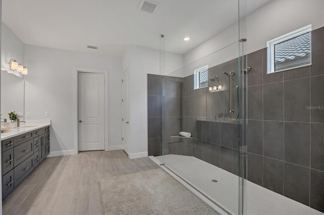 bathroom featuring vanity, wood-type flooring, and tiled shower