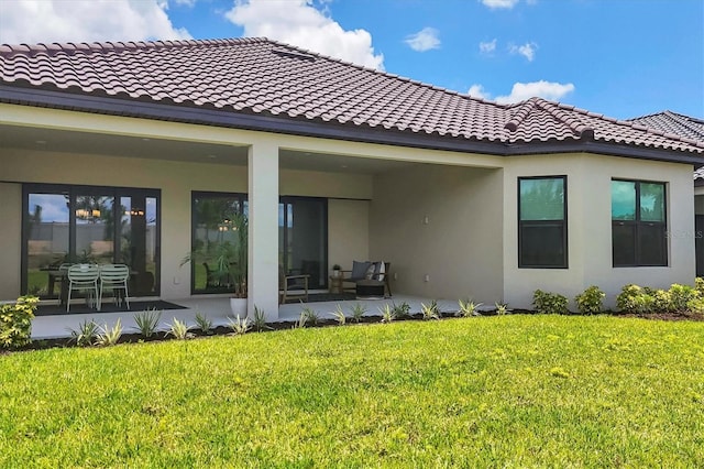 back of house with a lawn and a patio