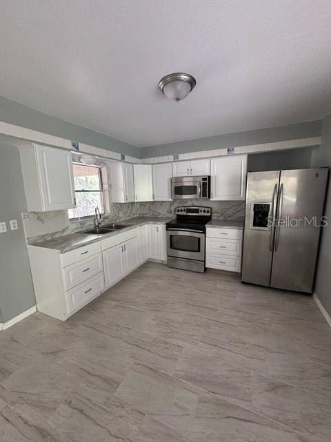 kitchen with sink, white cabinets, and appliances with stainless steel finishes