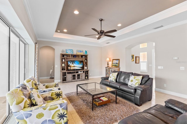 living room with a tray ceiling, crown molding, ceiling fan, and a healthy amount of sunlight