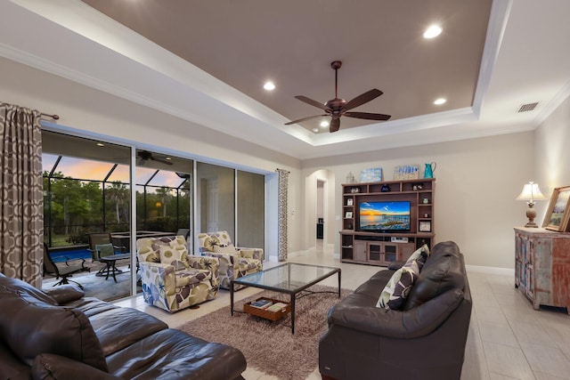 living room featuring light tile patterned floors, a raised ceiling, ceiling fan, and ornamental molding