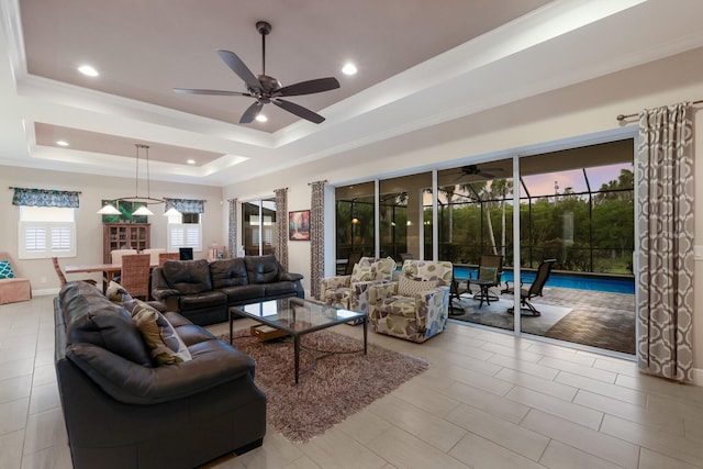 living room with ceiling fan, crown molding, and a tray ceiling