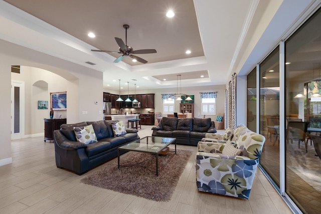 living room with a raised ceiling and ceiling fan