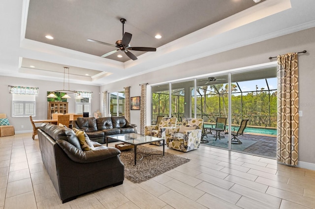 living room featuring a raised ceiling, ceiling fan, and ornamental molding