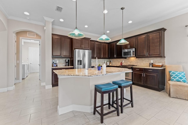 kitchen with pendant lighting, a center island with sink, stainless steel appliances, and dark brown cabinets