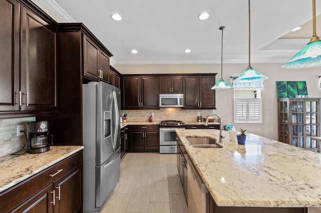 kitchen with sink, stainless steel appliances, crown molding, pendant lighting, and a kitchen island with sink