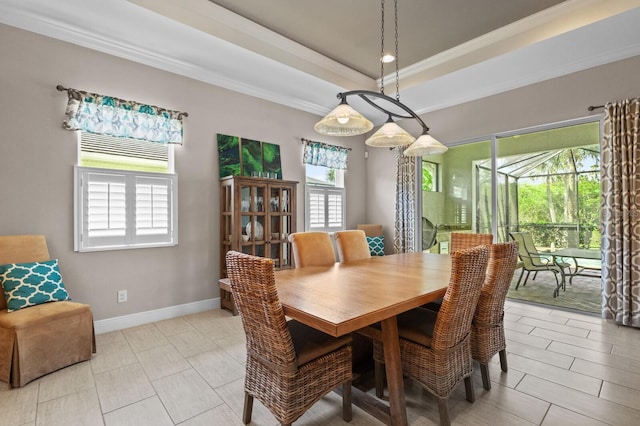 dining room with a raised ceiling, a wealth of natural light, and ornamental molding