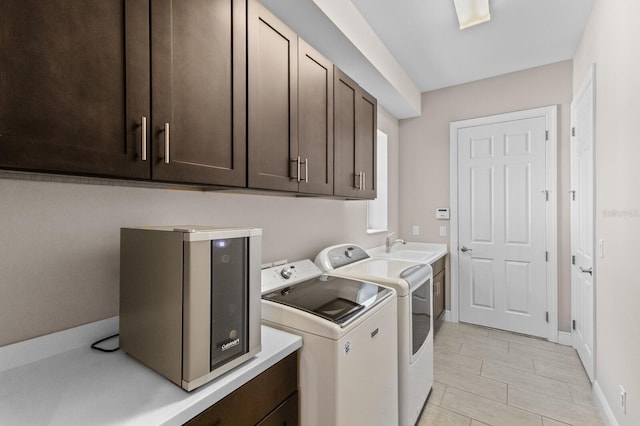 clothes washing area with washing machine and clothes dryer, sink, and cabinets