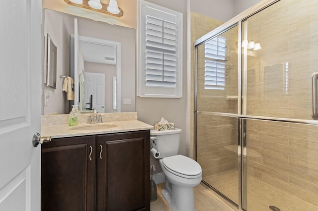 bathroom with tile patterned flooring, vanity, toilet, and a shower with shower door