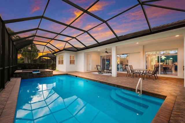 pool at dusk with a lanai, a patio area, an in ground hot tub, and ceiling fan