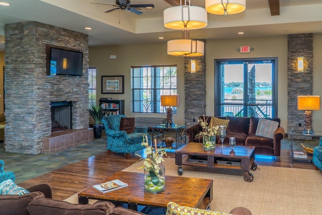 living room with a stone fireplace and ceiling fan