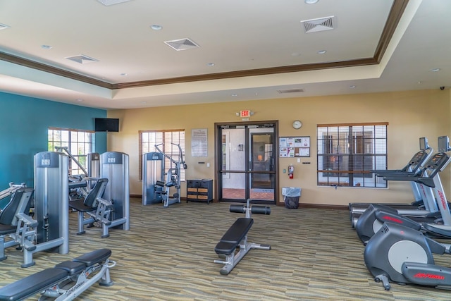 workout area featuring carpet floors, a tray ceiling, and ornamental molding