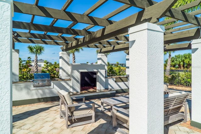 view of patio featuring an outdoor stone fireplace, a pergola, area for grilling, and exterior kitchen