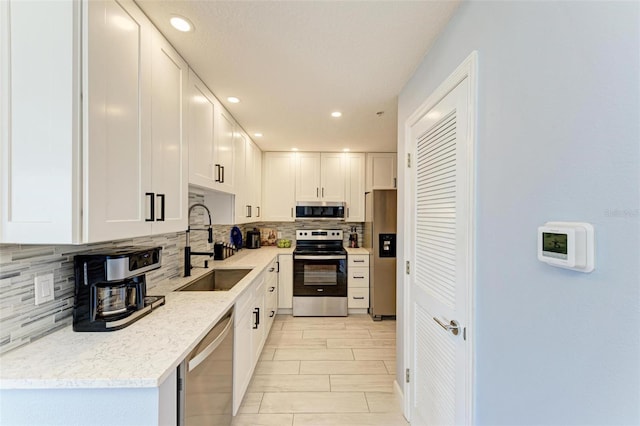 kitchen with sink, decorative backsplash, light stone countertops, appliances with stainless steel finishes, and white cabinetry