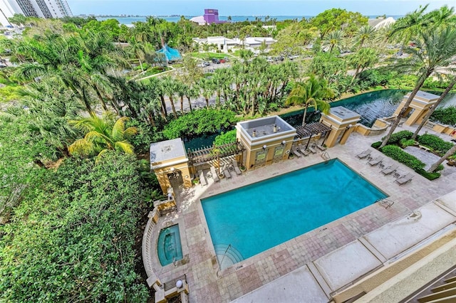 view of pool featuring a water view, area for grilling, a patio area, and a bar