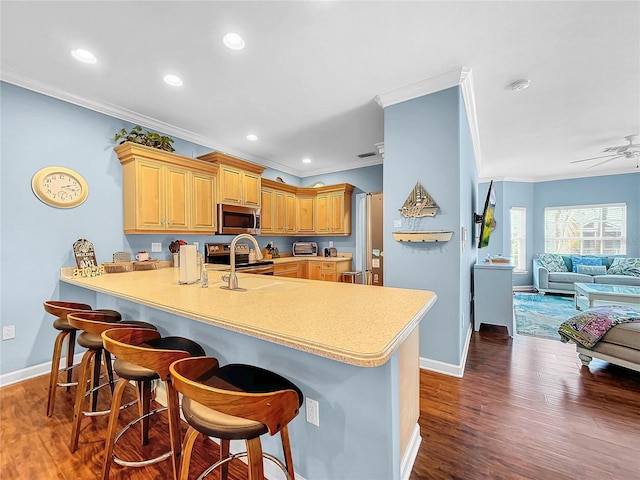 kitchen with ornamental molding, appliances with stainless steel finishes, a kitchen breakfast bar, and kitchen peninsula