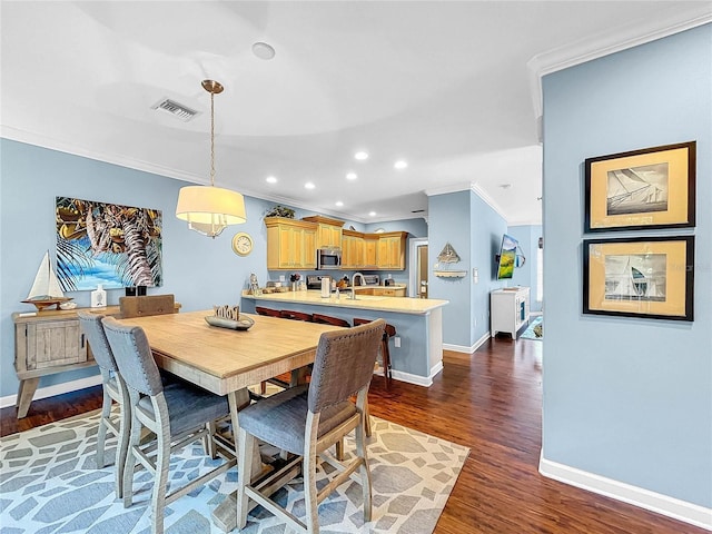 dining room with sink, ornamental molding, and dark hardwood / wood-style floors