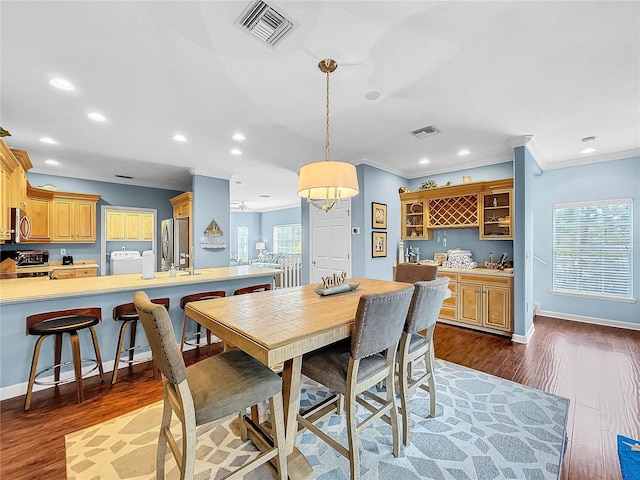 dining room featuring crown molding, plenty of natural light, dark hardwood / wood-style flooring, and washer / clothes dryer