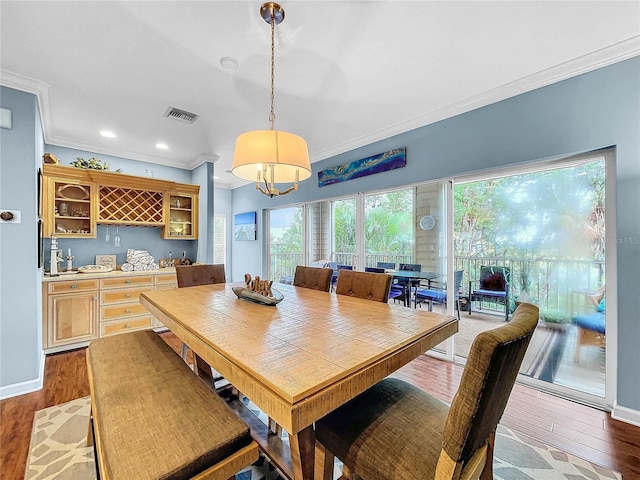 dining room featuring indoor bar, ornamental molding, and light hardwood / wood-style flooring