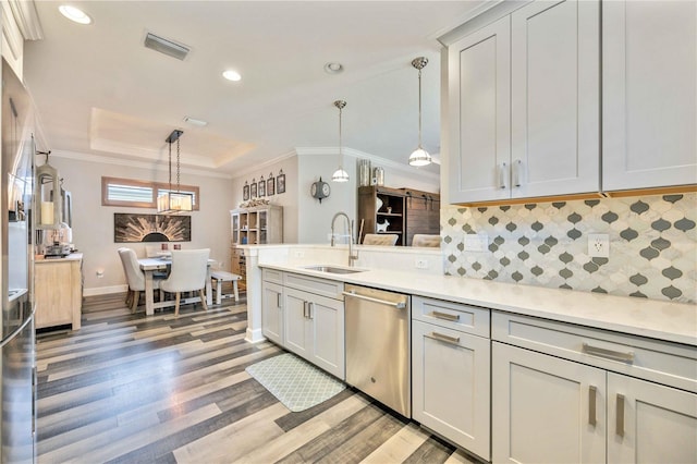 kitchen with dishwasher, a raised ceiling, sink, hanging light fixtures, and light hardwood / wood-style floors