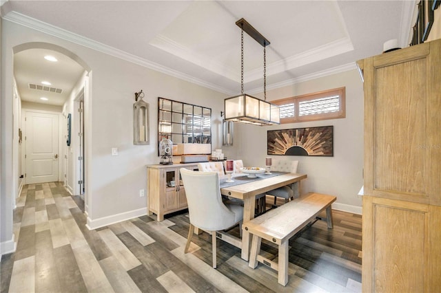 dining area featuring a raised ceiling, ornamental molding, and wood-type flooring