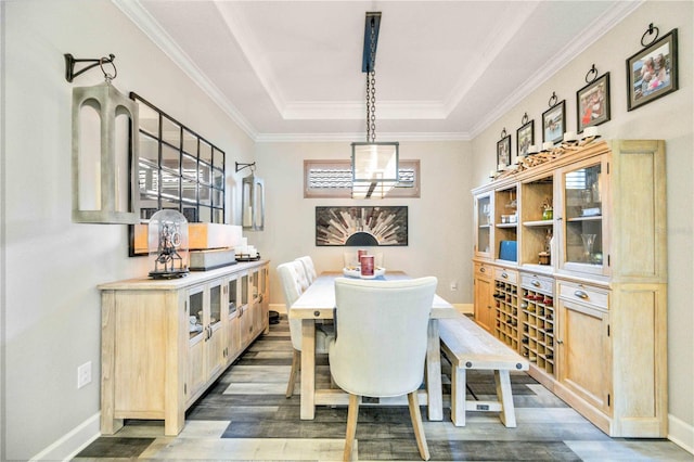 dining room with a raised ceiling, crown molding, and wood-type flooring