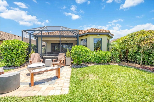 back of house featuring glass enclosure, ceiling fan, a yard, and a patio