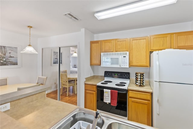 kitchen with decorative light fixtures, light hardwood / wood-style floors, and white appliances