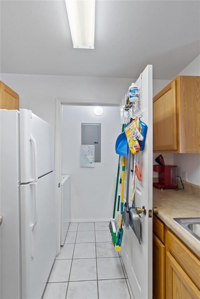 kitchen with light brown cabinetry, light tile flooring, washer / clothes dryer, and white fridge