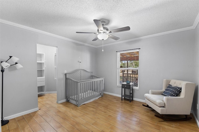 bedroom with ceiling fan, crown molding, a nursery area, and a textured ceiling